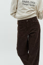 Brune zebramønstrede jeans med knaplukning og frontlommer, båret med en lys sweatshirt.