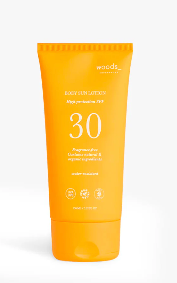 Orange tube med "WOODS", SPF 30, vegan, vandafvisende, duftfri, UVA/UVB og reef-sikker.